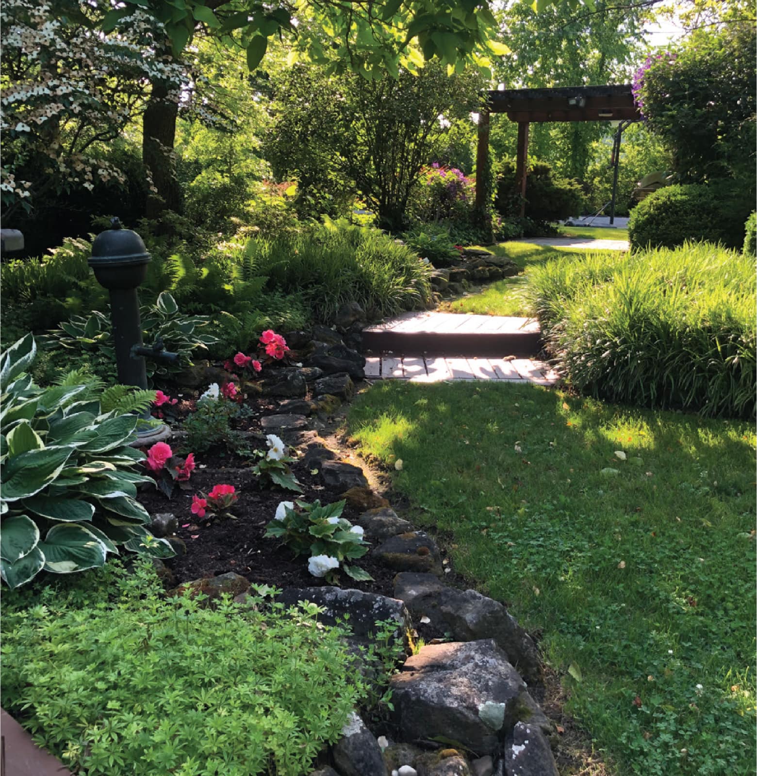 Landscaped garden with lawn, planting beds, and a stone path.