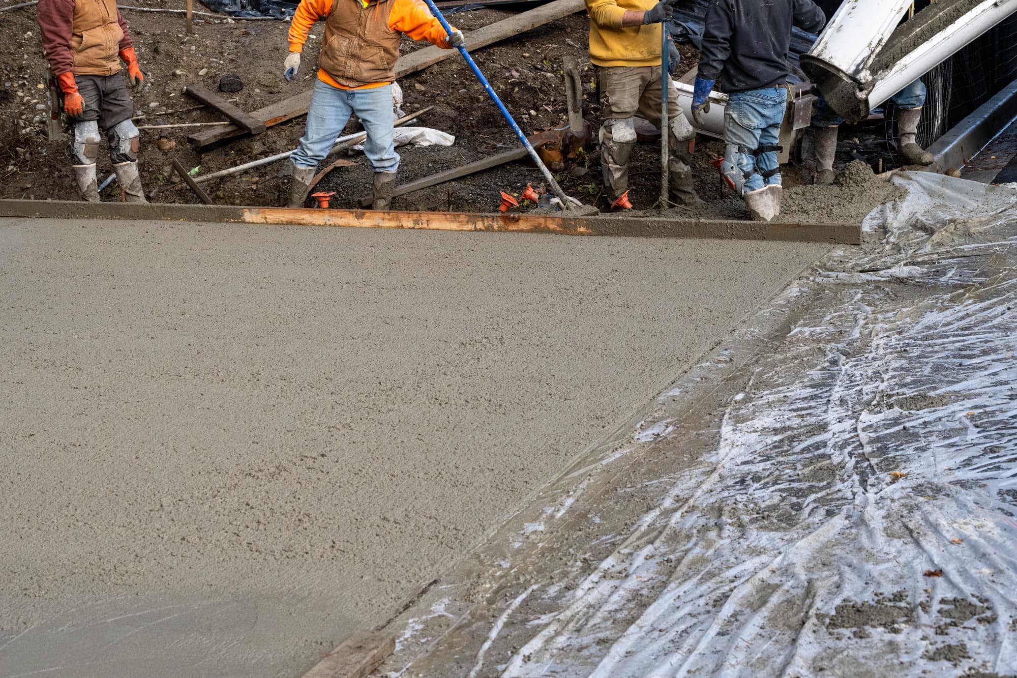 Construction crew finishing a poured concrete driveway